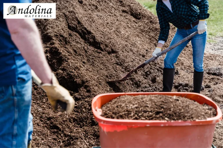 Two people shoveling mulch from a pile into a wheelbarrow