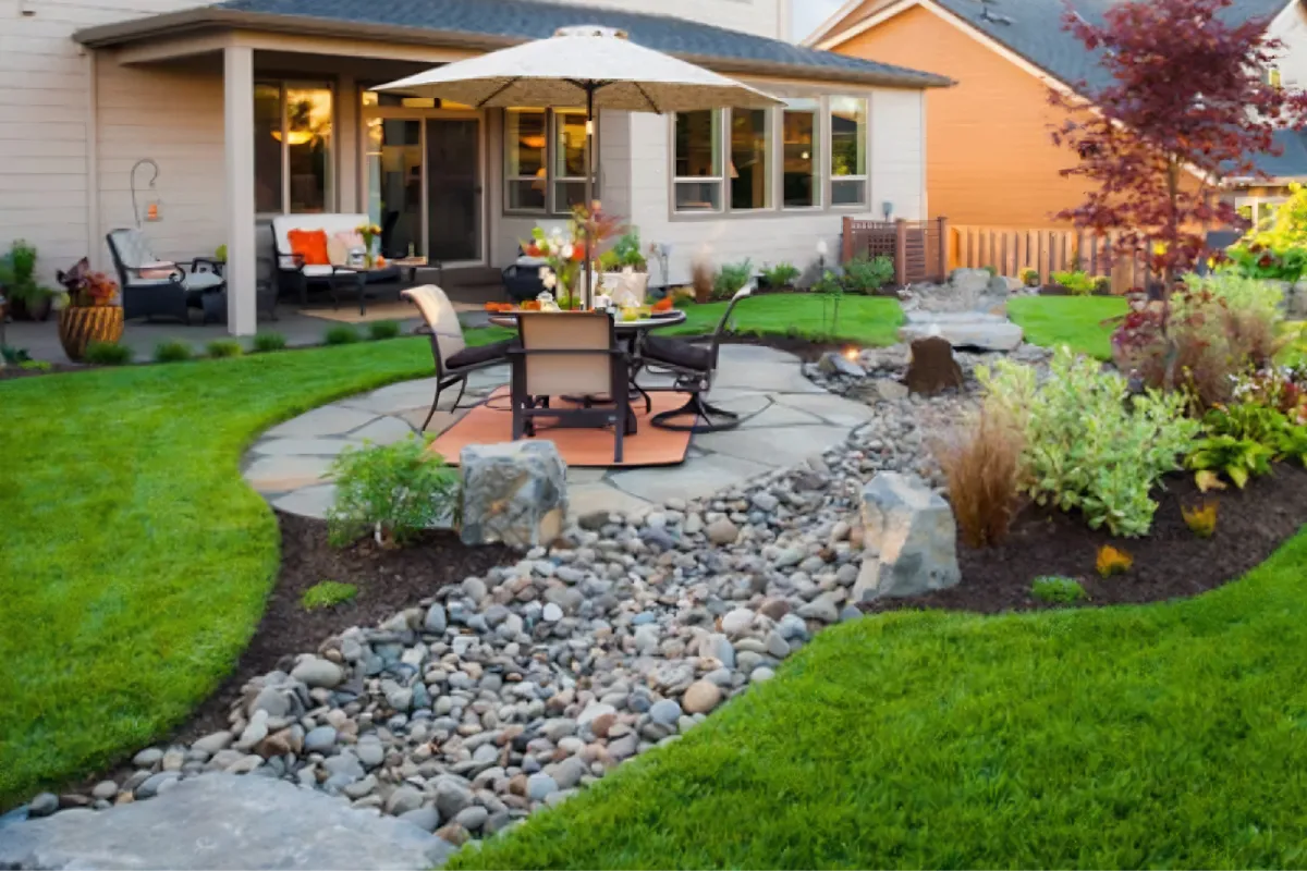 Backyard patio with a rock garden and landscaped lawn.