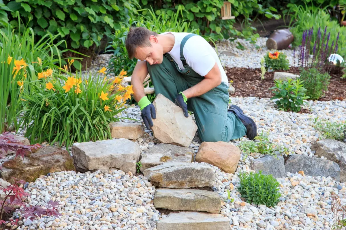 Landscaper placing rocks in a garden bed.