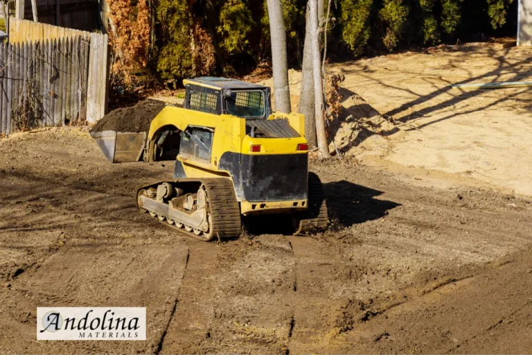 Skid steer moving soil for a landscape supply project.
