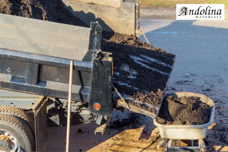 Topsoil being unloaded from a truck into a wheelbarrow.