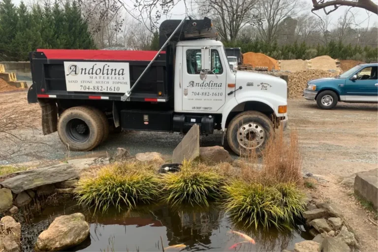 Landscape supply truck at a yard with stone and mulch.