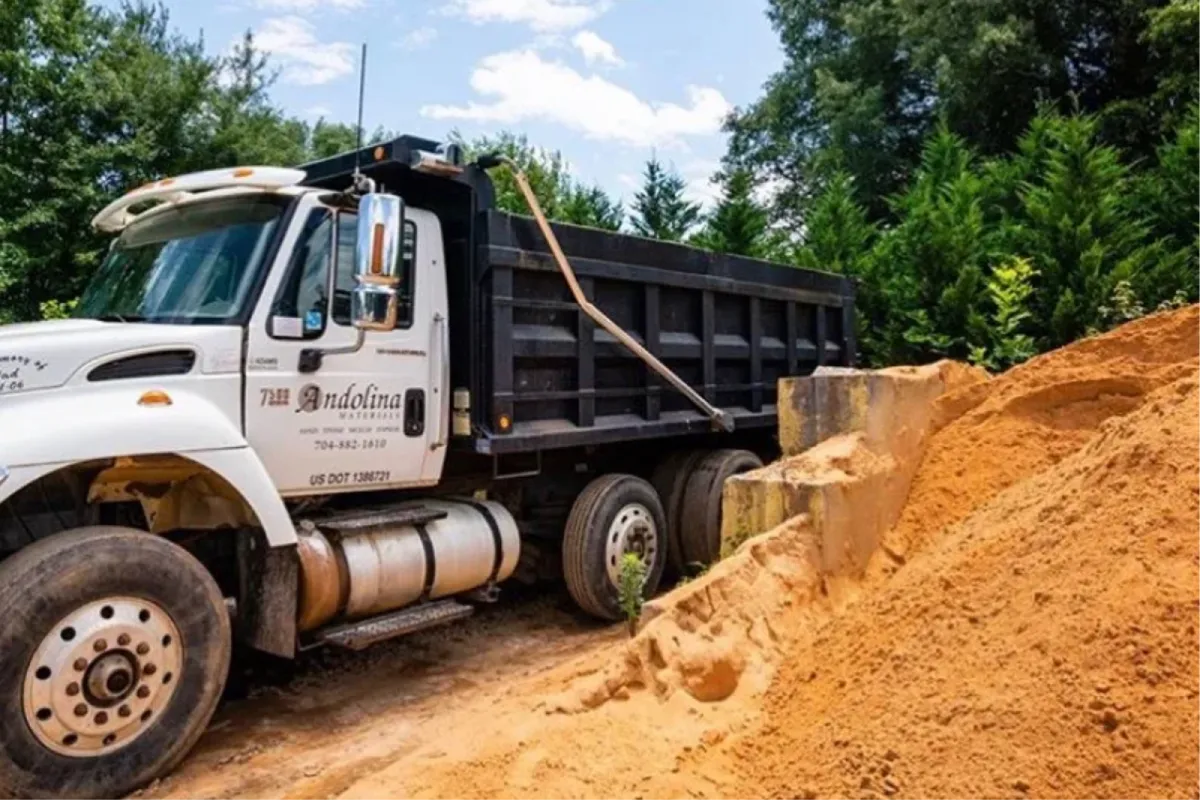 Landscape supply truck delivering bulk sand and materials.